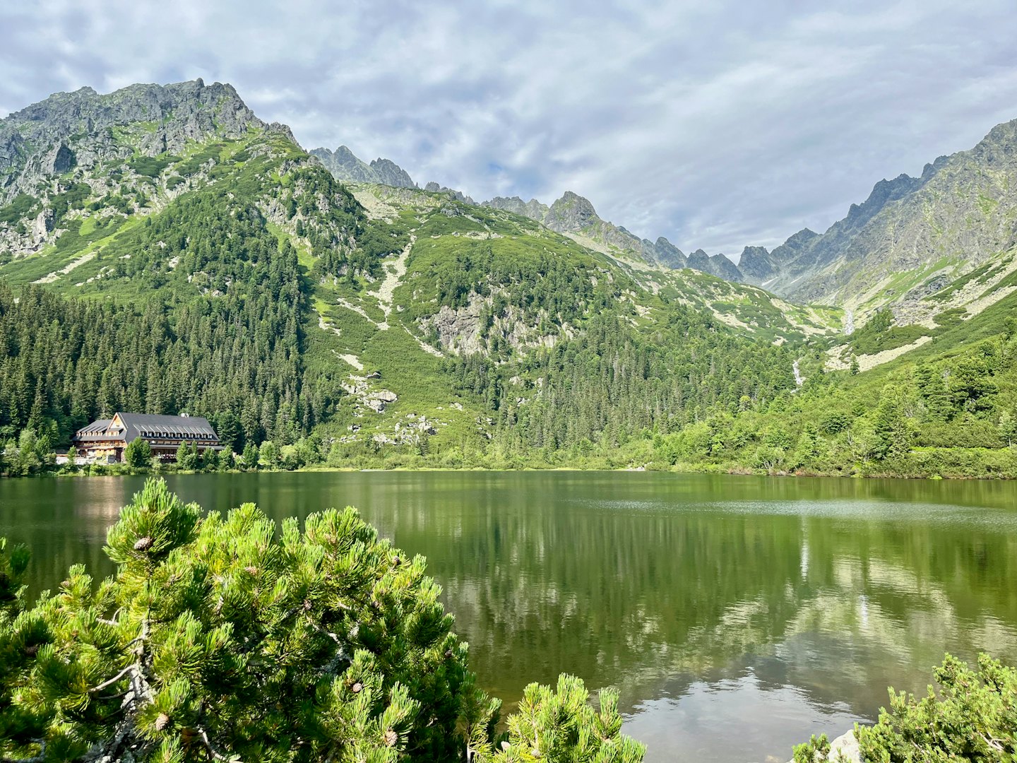 Riflesso di un lodge tradizionale in un lago di montagna circondato da foreste di pini.