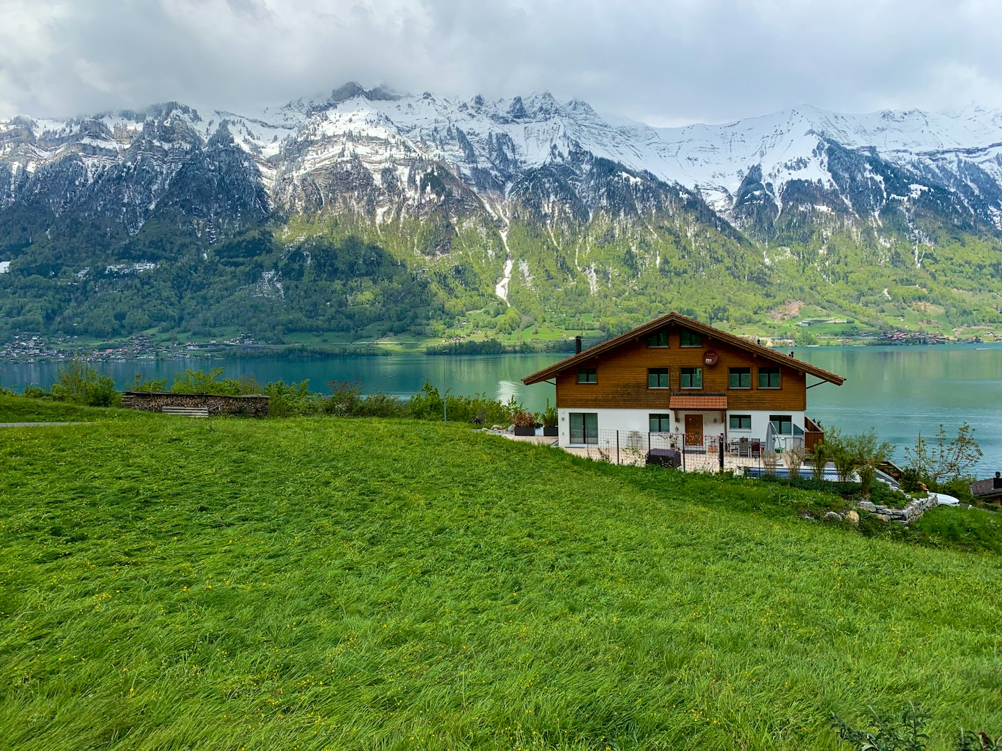 Chalet su una collina che domina un lago turchese e montagne.