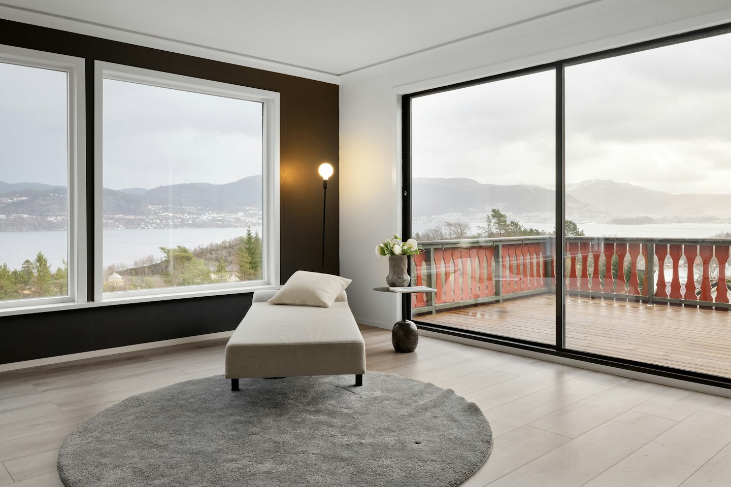 Chaise longue accanto a una finestra con vista su un lago panoramico.